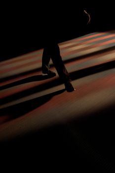 A silhouette of a person walking in a dark hallway with dramatic lighting and shadows.